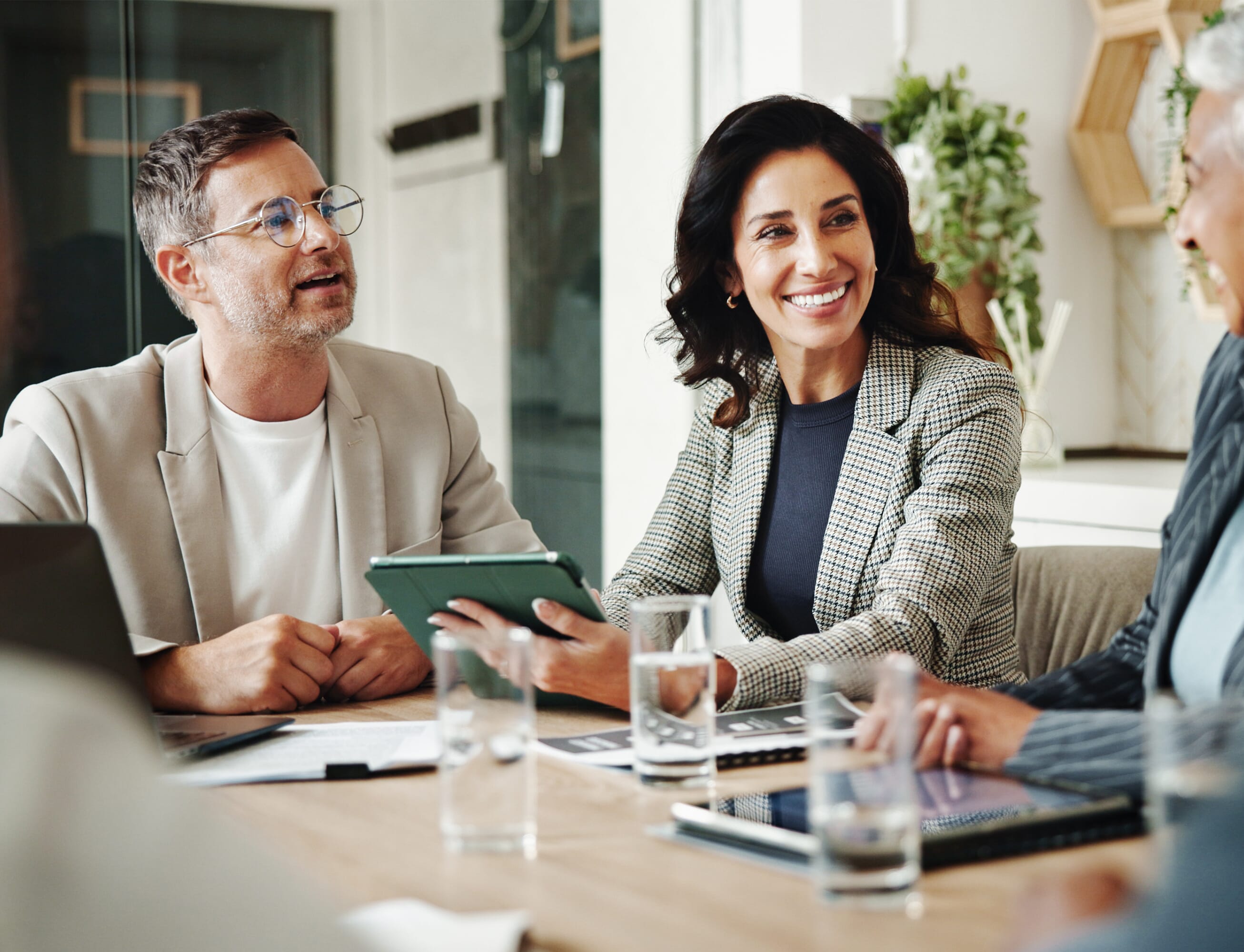 This image shows how we work with clients, in this image there are 3 smiley team members in a meeting. The main focus is on a happy smartly dressed lady wearing an ipad.