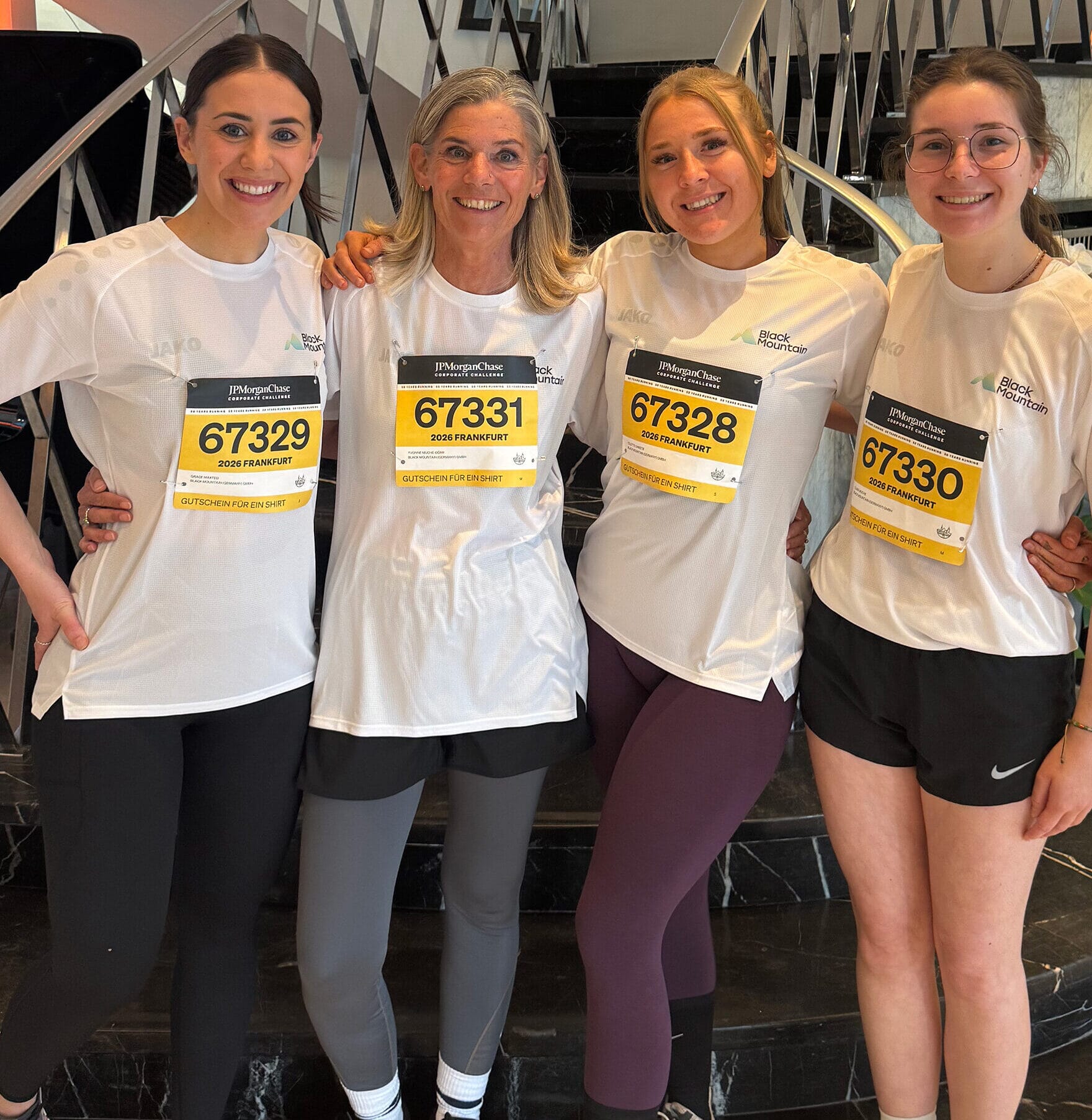 Left to right (Colette, Yvonne, Grace, and Clara) from Black Mountain pre 5K run event smiling with their branded tshirts and bibs on. #ESG